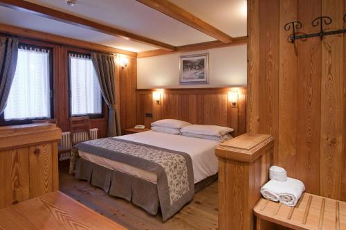 una camera con un letto in una stanza con pareti in legno di Hotel Castor a Champoluc