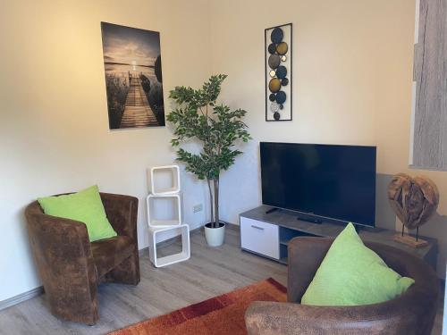 a living room with two chairs and a flat screen tv at Ferienwohnungen LpP Bad Suderode in Bad Suderode