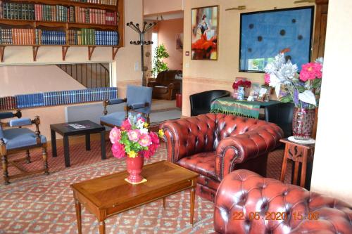 a living room with a leather couch and a table with flowers at Hôtel Le Castel in Brissac-Quincé