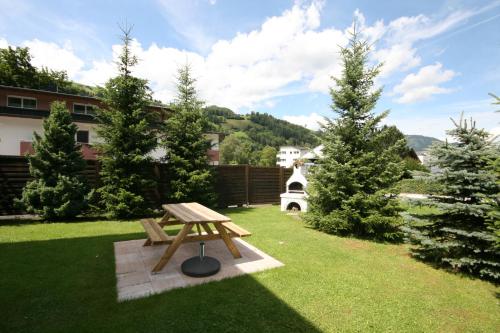a wooden picnic table in a yard with trees at Familienappartements Eder - Free entry to Tauern SPA Kaprun included in Kaprun