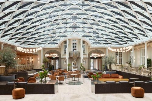 a lobby with a glass ceiling and tables and chairs at Villa Copenhagen in Copenhagen