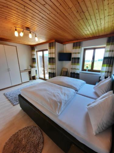 a large bed in a bedroom with a wooden ceiling at Pension Kreuzinger, 5310 Tiefgraben in Mondsee