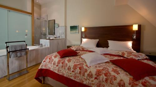 a bedroom with a bed and a bathroom with a sink at Pałac Pakoszów Schlosshotel Wernersdorf in Jelenia Góra