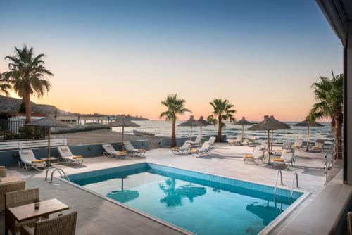 une piscine avec des chaises et l'océan en arrière-plan dans l'établissement Compass beach, à Stalida