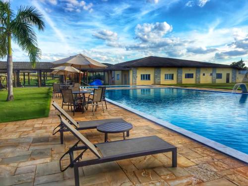 a swimming pool with a table and chairs next to it at Pousada Haras Santa Rita in Poconé
