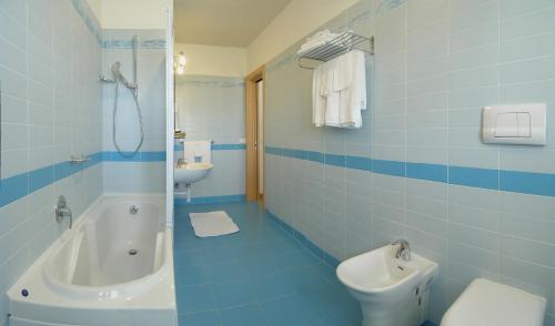 Baño azul con bañera, aseo y lavamanos en Hotel Bertha Fronte Mare, en Lido di Jesolo