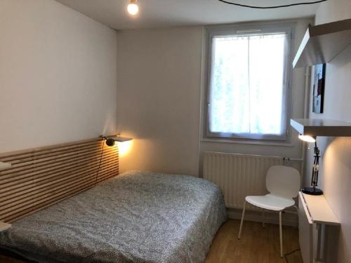 a bedroom with a bed and a window and a chair at Chambre paisible tout confort in Courcouronnes