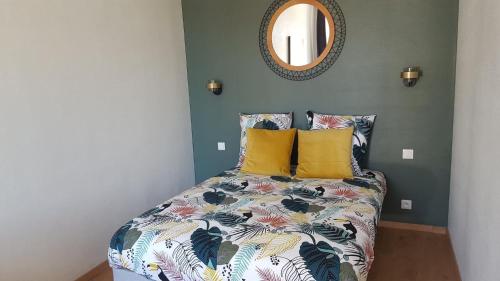 ein Schlafzimmer mit einem Bett mit gelben Kissen und einem Spiegel in der Unterkunft Au Martray in Paimpol