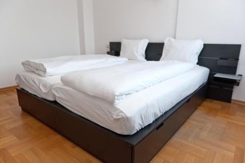 1 cama grande con sábanas blancas y almohadas. en Villa Verona en Cracovia