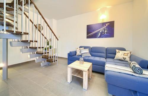 a living room with a blue couch and stairs at Oak Meadow Apartment in Dobrinj