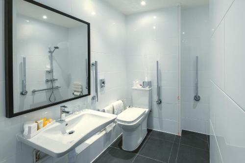 a bathroom with a sink and a toilet and a mirror at Crowne Plaza Plymouth by IHG in Plymouth
