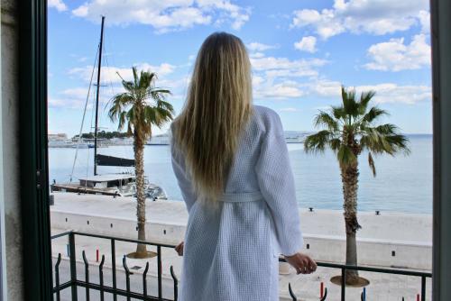 a woman looking out a window at the beach at Galeria Valeria Seaside Downtown - MAG Quaint & Elegant Boutique Hotels in Split