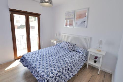 une chambre avec un lit avec une couette bleue et une fenêtre dans l'établissement ATALAYAS 153, à Peñíscola