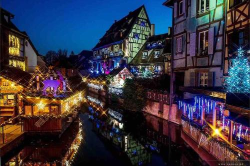 a city lit up at night with christmas lights at Coeur Alsace in Colmar