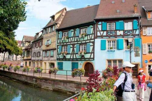 a man standing in front of a building next to a river at Coeur Alsace in Colmar