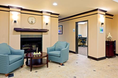 a living room with two chairs and a fireplace at Holiday Inn Express Hotel & Suites Syracuse North Airport Area by IHG in Cicero