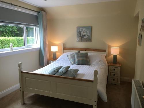 a bedroom with a bed with two lamps and a window at Crescent Corner, Inverness in Inverness