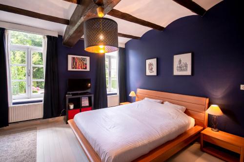 um quarto com uma cama com uma parede azul em Au Petit Dragon em Mons