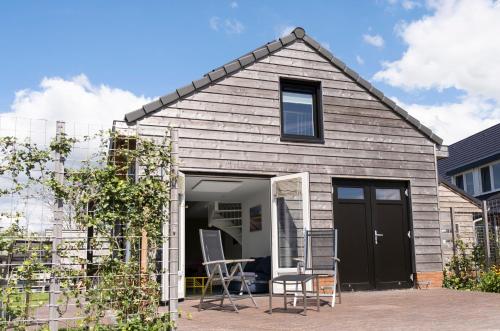a small house with a black door and a patio at Tulpenhoek in Akersloot