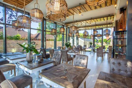 un restaurante con mesas, sillas y lámparas de araña en Hotel Achterum Greetsiel, en Greetsiel
