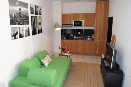 a living room with a green couch and a kitchen at Cosy apartment in the center of Brussels in Brussels