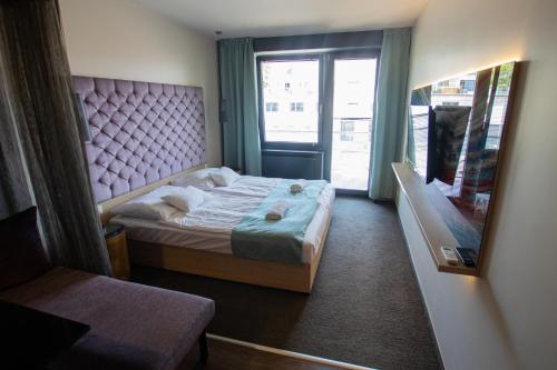 1 dormitorio con 1 cama con cabecero rosa y ventana en VISION APARTMAN en Sárvár