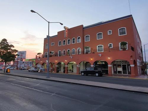 een rood gebouw op een straat met auto's aan de voorkant bij Hotel el Mayo Inn in Culiacán