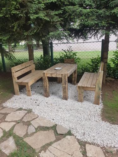 two wooden benches and a picnic table in a park at Belette Apartments & Park in Nikšić