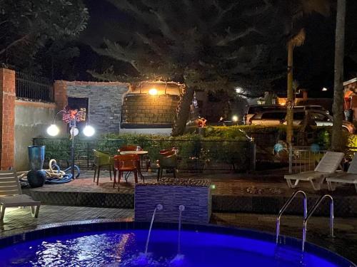 a swimming pool at night with a table and chairs at Lake Victoria Country Home in Entebbe