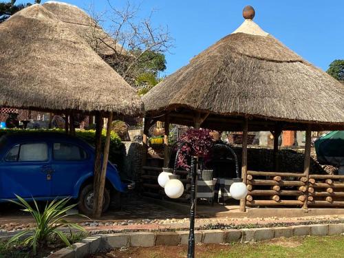 a blue car parked under two straw umbrellas at Lake Victoria Country Home in Entebbe