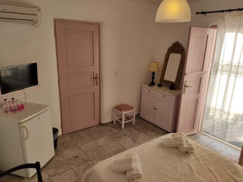 a bedroom with a bed and a mirror and a tv at Porto Sikinos Hotel in Alopronia