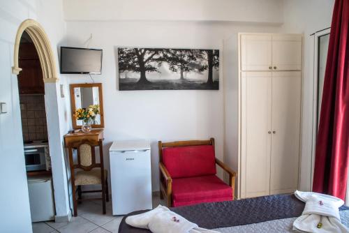 uma sala de estar com uma cadeira vermelha e uma televisão em Empress Corfu em Perama