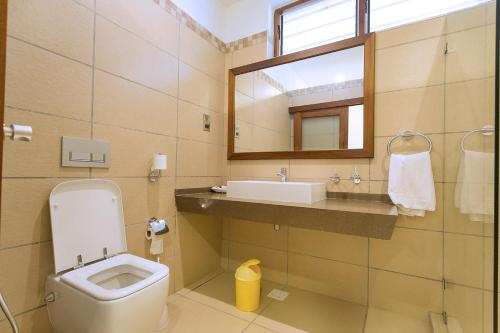 a bathroom with a toilet and a sink and a mirror at Travellers Beach Hotel in Mombasa