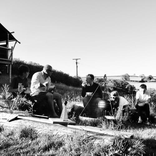 a group of people sitting in the grass at Brackenhill Glamping - Safari Tent with Hot Tub in Ivybridge
