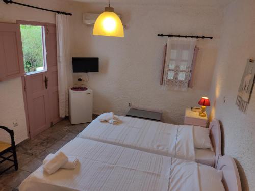 a bedroom with two white beds and a television at Porto Sikinos Hotel in Alopronia