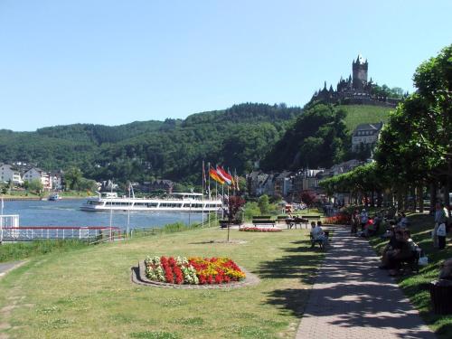 a park with flowers and a cruise ship in the water at Hotel Villa Tummelchen in Cochem