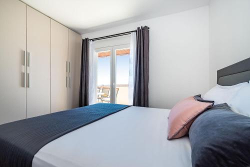 a bedroom with a large white bed with a window at Merita Apartments with Pool in Sveti Filip i Jakov