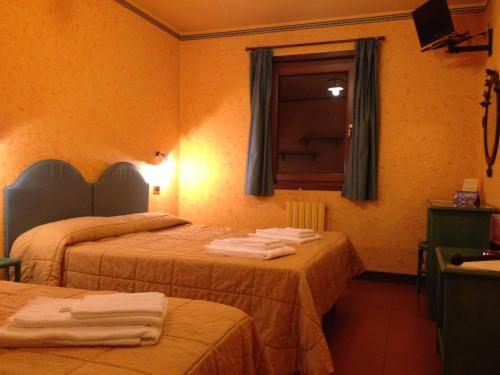 a hotel room with two beds with towels on them at Hotel I Pionieri in Abetone
