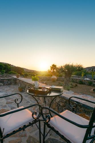 a table and two chairs with the sunset in the background at Yiannis Retreat in Káto Zákros