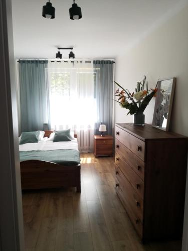 a bedroom with a bed and a dresser and a window at Apartament przy Starówce in Sandomierz