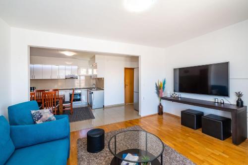 a living room with a blue couch and a flat screen tv at Merita Apartments with Pool in Sveti Filip i Jakov