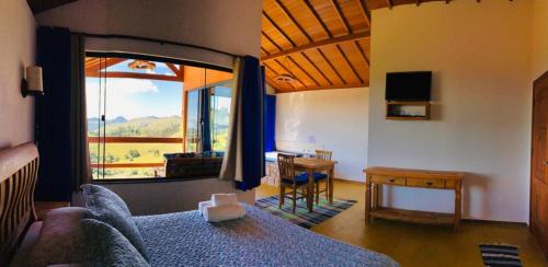 ein Schlafzimmer mit einem Bett und einem großen Fenster in der Unterkunft Chalés Terras Altas in Gonçalves
