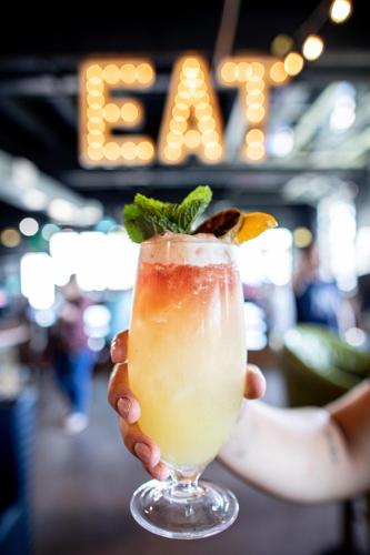 a person holding a drink with a fruit garnishment at Carlsbad by the Sea Hotel in Carlsbad