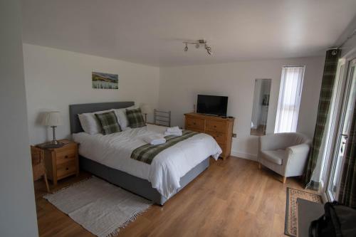 a bedroom with a bed and a television and a chair at Portree Garden Room in Portree