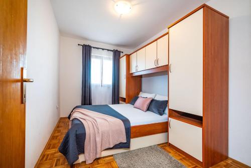 a small bedroom with a bed and a window at Merita Apartments with Pool in Sveti Filip i Jakov