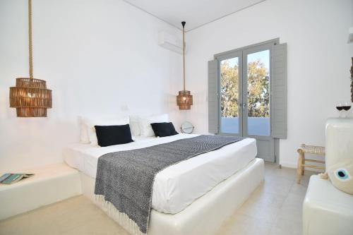 um quarto branco com duas camas e uma janela em Aegeeis em Perissa
