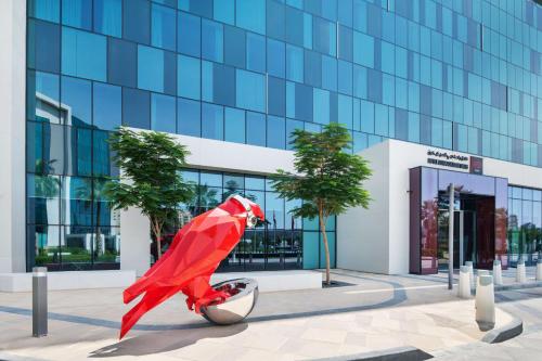 uma grande estátua vermelha de super-herói em frente a um edifício em Radisson RED Dubai Silicon Oasis em Dubai