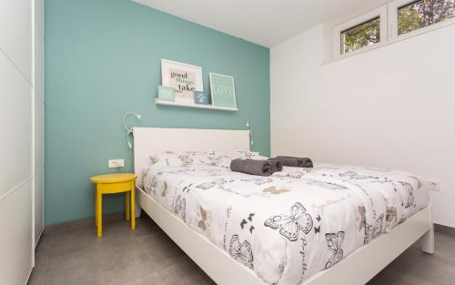 a bedroom with a bed and a yellow table at Happy Apartments Baška in Baška
