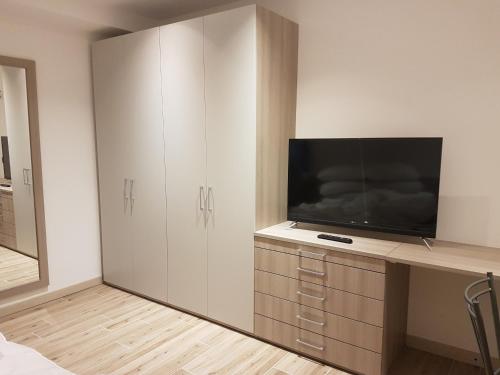 - une chambre avec une télévision sur une commode et une armoire dans l'établissement Alloggio Casa Talvena XL, à Longarone