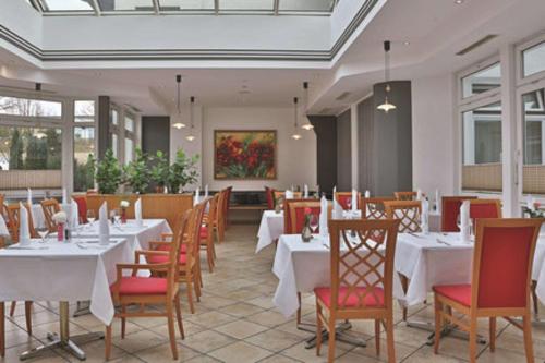 un restaurante con mesas y sillas blancas y una pintura en Hotel Empfinger Hof, Sure Hotel Collection by Best Western, en Empfingen